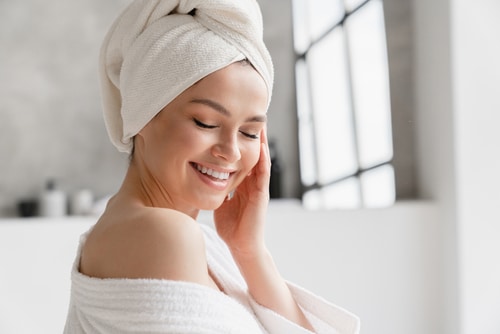 woman in spa bathrobe and towel relaxing after taking shower bath
