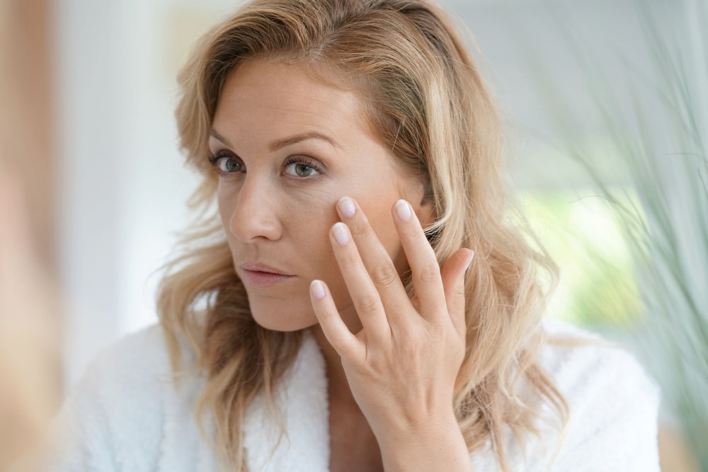 A woman looking in the mirror and considering UltraClear laser treatment in Encino